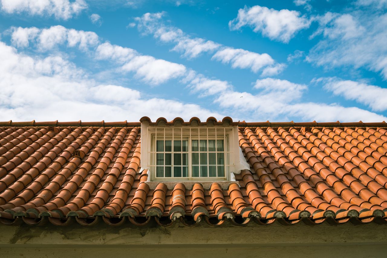 services-01 Close-up of a terracotta tiled roof with a skylight window in sunny Marbella, Spain.